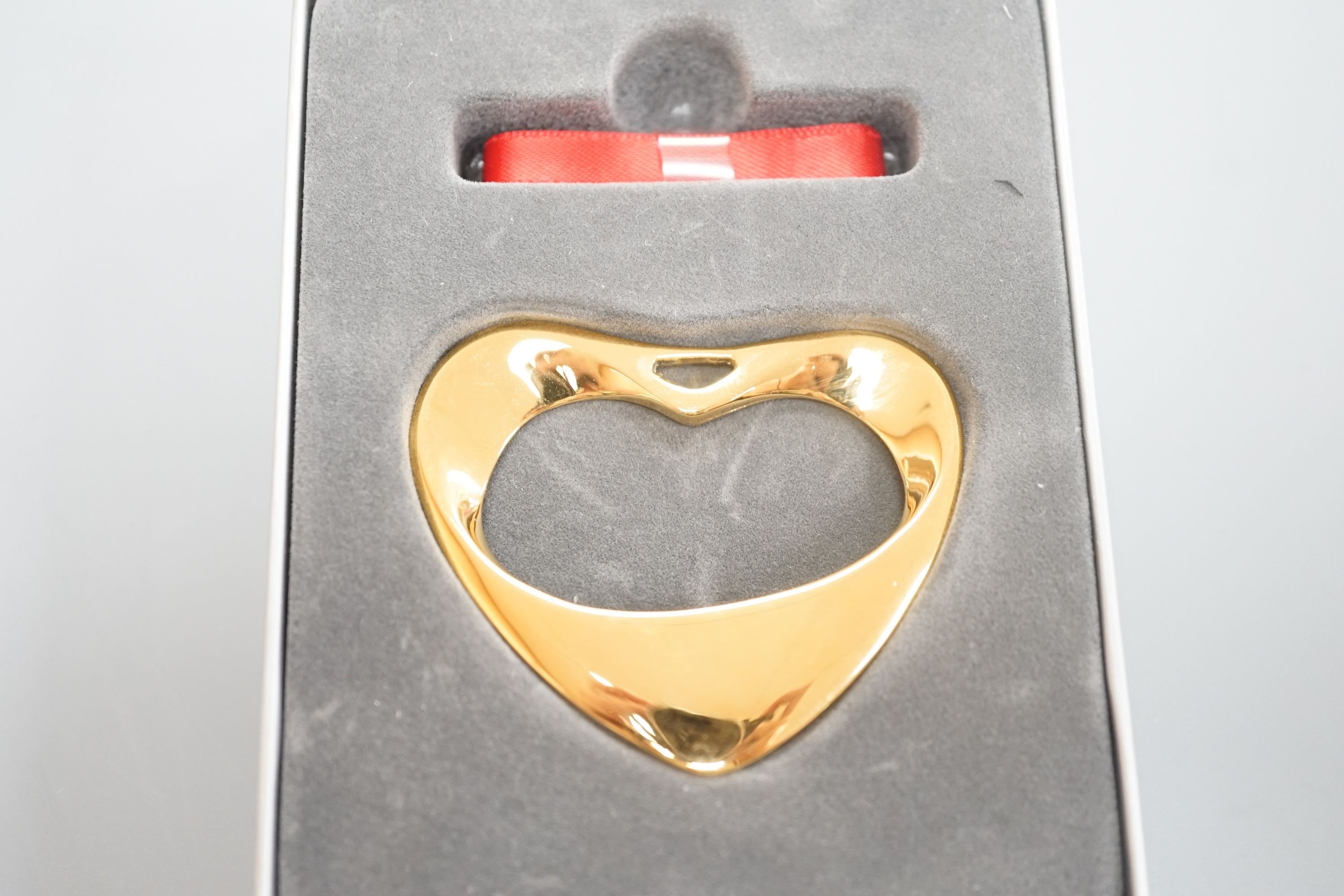 A modern Georg Jensen gold plated open work heart shaped pendant, no. 152A, width 55mm, with red and blue sashes and box.